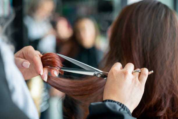 Hair being cut with scissors at a salon.