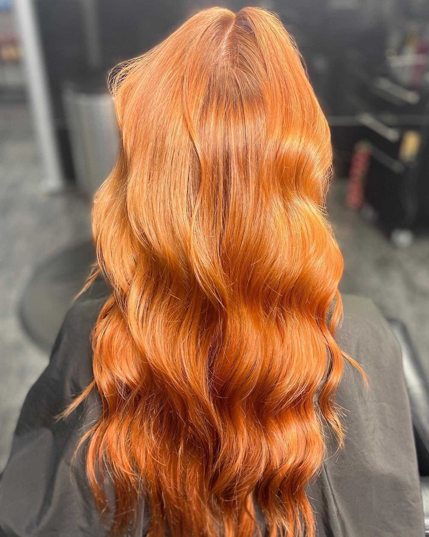 Long, wavy red-orange hair styled elegantly in a salon.